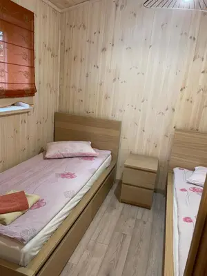 two beds in a room with wooden walls at Atostogų namelis in Kurėnai