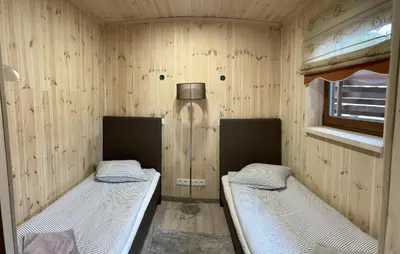 two beds in a room with wooden walls at Atostogų namelis in Kurėnai