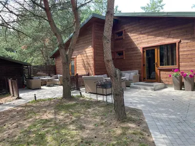 a wooden house with chairs and tables in front of it at Atostogų namelis in Kurėnai