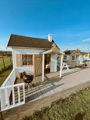 a small house on a wooden deck with a grill at HYTTE - Cozy Stay For Families & Friends in Jagėlonys Kalniniai