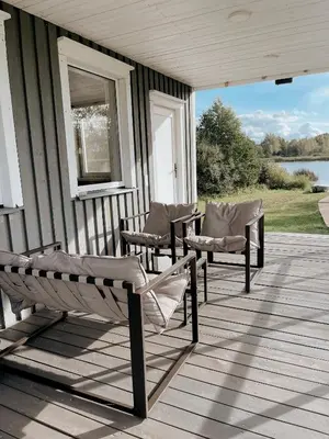 a porch with chairs and a window on a house at HYGGE Sauna&Fishing House in Jagėlonys Kalniniai