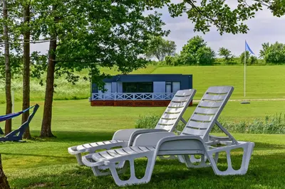 two white lawn chairs sitting in the grass at Sodyba Svayos in Zarasai