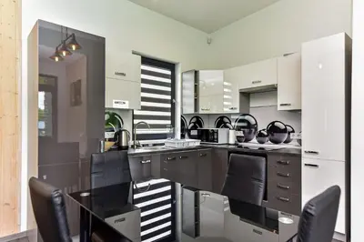 a kitchen with white cabinets and black chairs at Sodyba Svayos in Zarasai