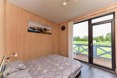a bedroom with a bed and a large window at Sodyba Svayos in Zarasai