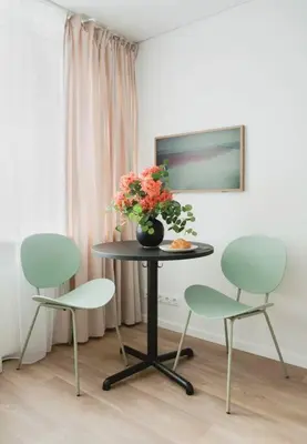 a table with three chairs and a vase with flowers on it at Apartment in Žvėrynas in Vilnius