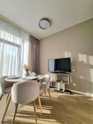 a living room with a table and chairs and a tv at ALEGRE apartment in Druskininkai