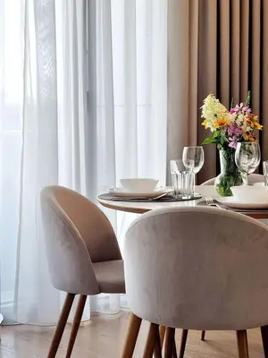 a dining room table with chairs and a vase of flowers at ALEGRE apartment in Druskininkai