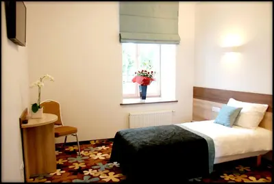 a bedroom with a bed and a window with a vase of flowers at Algiro Hotel in Kaunas