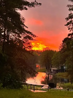 a sunset over a lake with a boat dock at Namelis Strazdas in Molėtai
