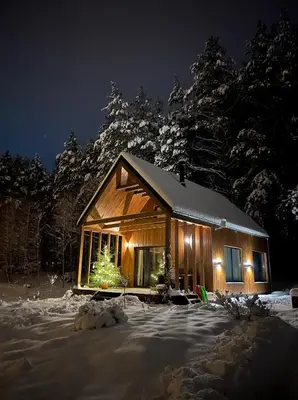a log cabin in the snow at night at Namelis Strazdas in Molėtai