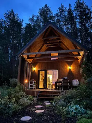 a cabin in the woods at night with the door open at Namelis Strazdas in Molėtai