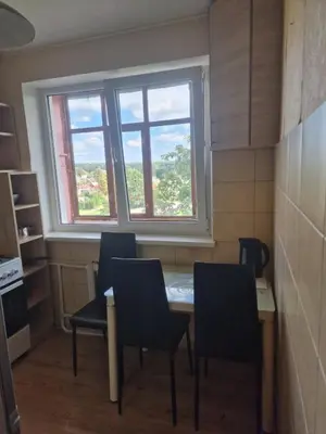 a kitchen with a table and chairs and a window at Butas 34 in Šiauliai
