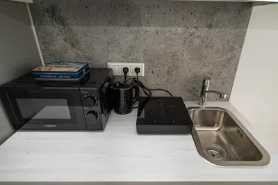 a kitchen counter with a microwave and a sink at Studios K1A in Vilnius