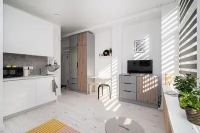 a kitchen with white cabinets and a tv and a table at Studios K1A in Vilnius