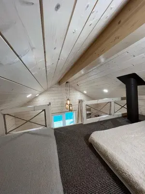 a bedroom with a bed and a wooden ceiling at Milkės Karibai - poilsio namelis su sauna ir kubilu in Statiškė