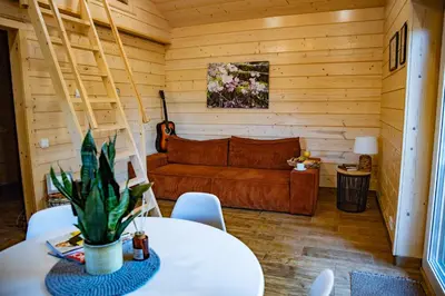 a living room with a couch and a table at Milkės Karibai - poilsio namelis su sauna ir kubilu in Statiškė
