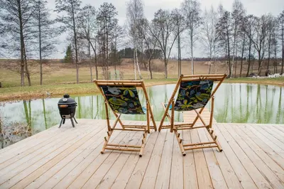 two chairs sitting on a dock near a body of water at Milkės Karibai - poilsio namelis su sauna ir kubilu in Statiškė