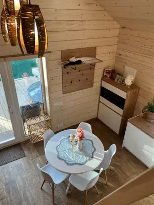 a kitchen with a table and chairs in a room at Milkės Karibai - poilsio namelis su sauna ir kubilu in Statiškė