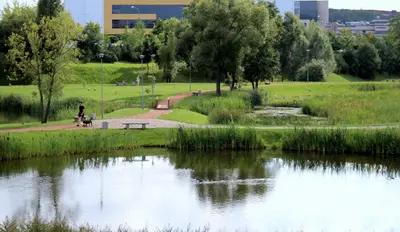 a person sitting on a bench next to a pond at The cosiest apartment in Vilnius in Vilnius