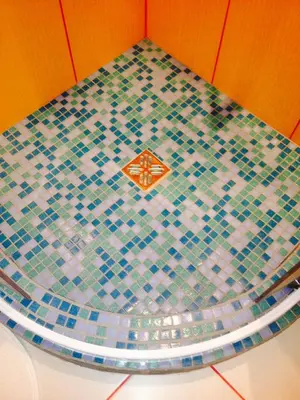 a bathroom floor with a blue and green mosaic tile at A Cozy Central Studio in Druskininkai