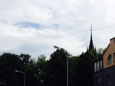 a street light with a church steeple in the background at A Cozy Central Studio in Druskininkai
