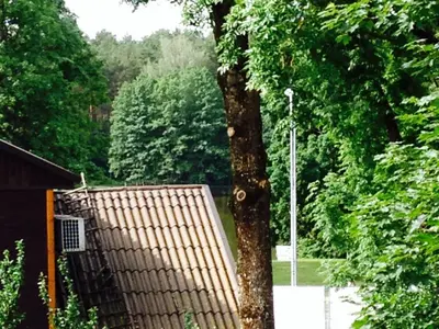 a tree with a fence next to a building at A Cozy Central Studio in Druskininkai
