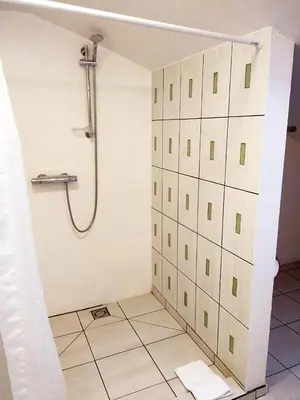 a bathroom with a shower and a tiled floor at Perlos Apartamentai 14 in Birštonas