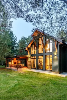 a house with large glass windows and a green yard at Ranča in Molėtai