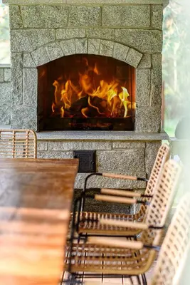 a fireplace with a table and chairs in front of it at Ranča in Molėtai