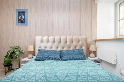 a bedroom with a large bed with a tufted headboard at Premium City Center Lukiskiu Apartment in Vilnius
