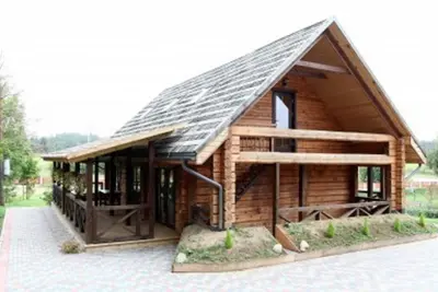 a large wooden cabin with a gambrel roof at Liūto kalnas in Trakai