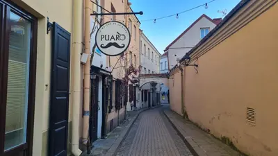an alley with a pulao sign on a building at Rehouse, Antokolskio 13 in Vilnius