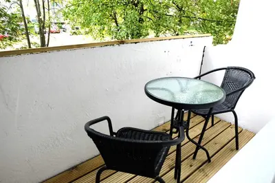 a glass table and two chairs on a balcony at Jaukus Koko butas 1 aukšte in Kaunas