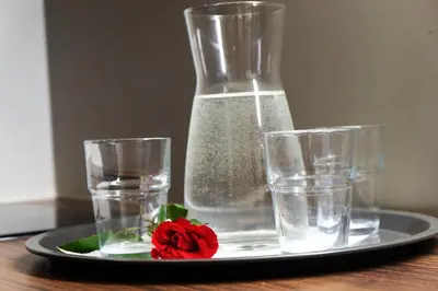 a plate with a vase and glasses on a table at Jaukus Koko butas 1 aukšte in Kaunas