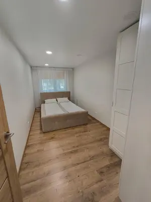 a bedroom with a bed and a wooden floor at Tukas Apartment in Marijampolė