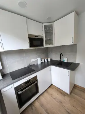 a kitchen with white cabinets and a sink at Tukas Apartment in Marijampolė