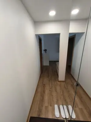 a bathroom with white walls and wooden floors and a mirror at Tukas Apartment in Marijampolė