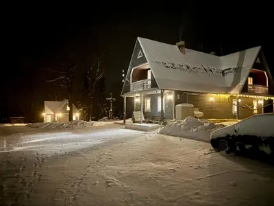 a house is covered in snow at night at Maple House - Sodyba Tarp Klevų in Utena
