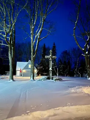 a statue in the snow in front of a church at Maple House - Sodyba Tarp Klevų in Utena