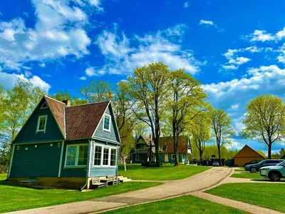 a green house with a gambrel roof on a lawn at Maple House - Sodyba Tarp Klevų in Utena