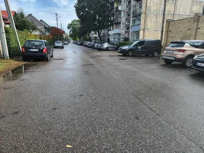 an empty street with cars parked on the side of the road at near the old town in Kaunas