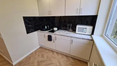 a small kitchen with white cabinets and a microwave at near the old town in Kaunas