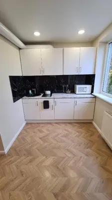 a kitchen with white cabinets and a wooden floor at near the old town in Kaunas