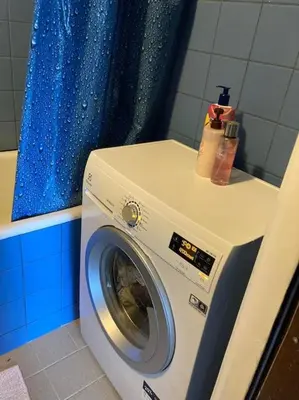a washing machine in a bathroom with a blue shower curtain at ShortStopPasilaiciai in Vilnius