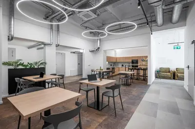a room with tables and chairs and a kitchen at We LOFT in Vilnius