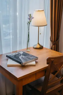 a laptop on a desk with a lamp and a vase of flowers at CATHEDRAL Old Town Suites in Vilnius