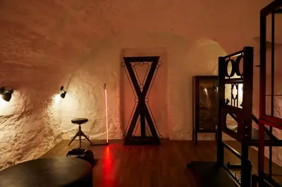 a room with a wooden floor and a room with a ladder at BDSM Black Apartments in Vilnius