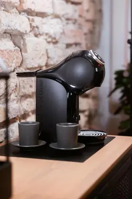 a coffee machine sitting on a table with two cups at BDSM Black Apartments in Vilnius