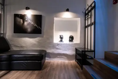 a living room with a black leather couch and two sculptures at BDSM Black Apartments in Vilnius