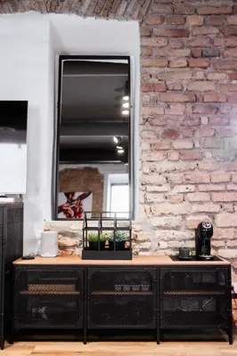 a black dresser with a mirror on a brick wall at BDSM Black Apartments in Vilnius